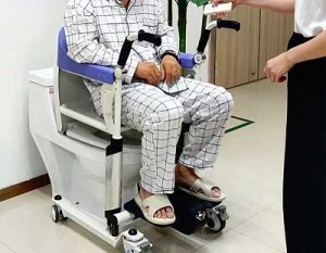 Un enfermo sentado sobre el wc en la plataforma de traslado Moovy de Ortopedia Moverte