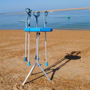 Soporte trípode para muletas anfibias manteniéndolas en vertical en la playa