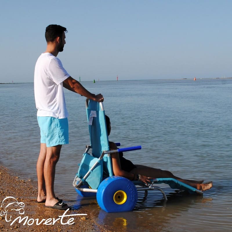 Llegar hasta el agua con silla de ruedas anfibia guiada por acompañante en playa accesible