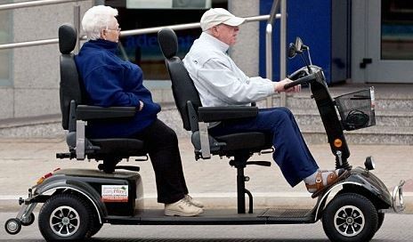 Dos personas mayores pasean comodamente sentados en un scooter biplaza 